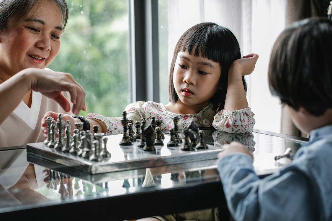 Children playing chess with a grandmother