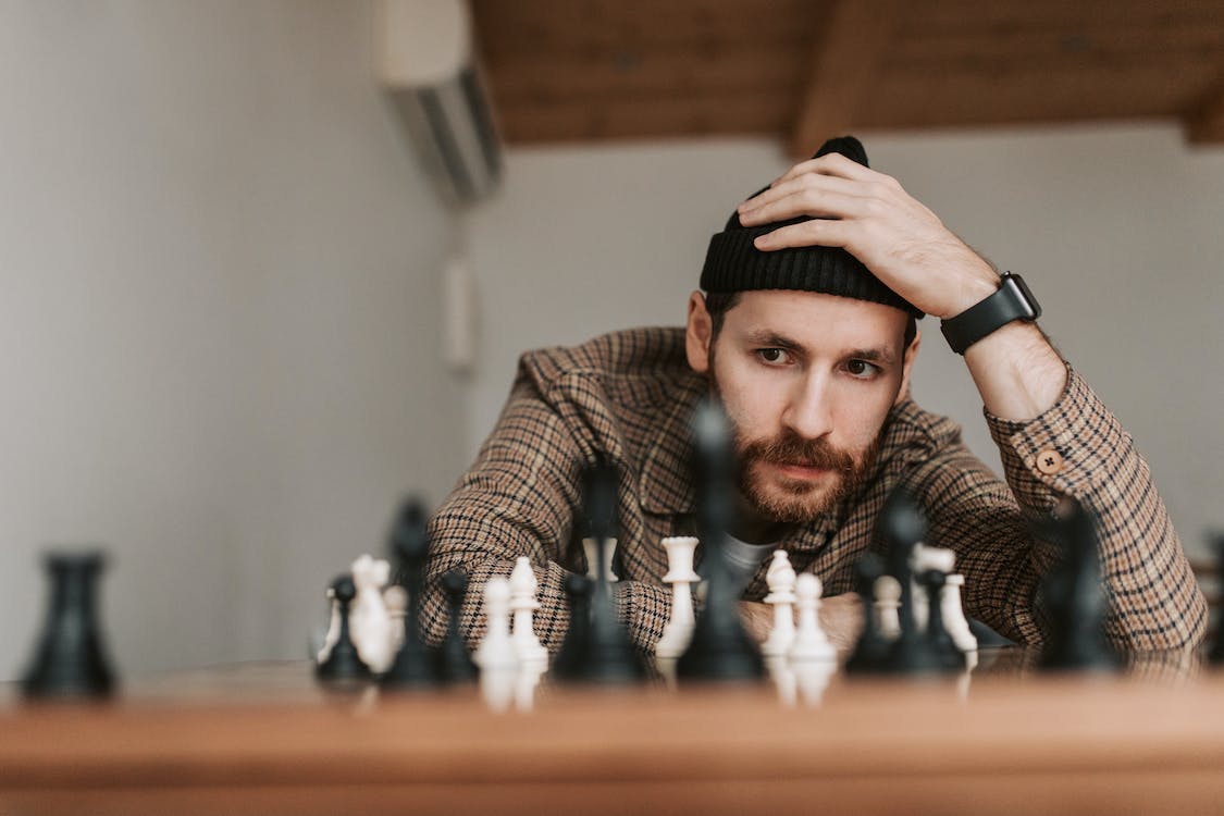 Man focused on chessboard holding his head